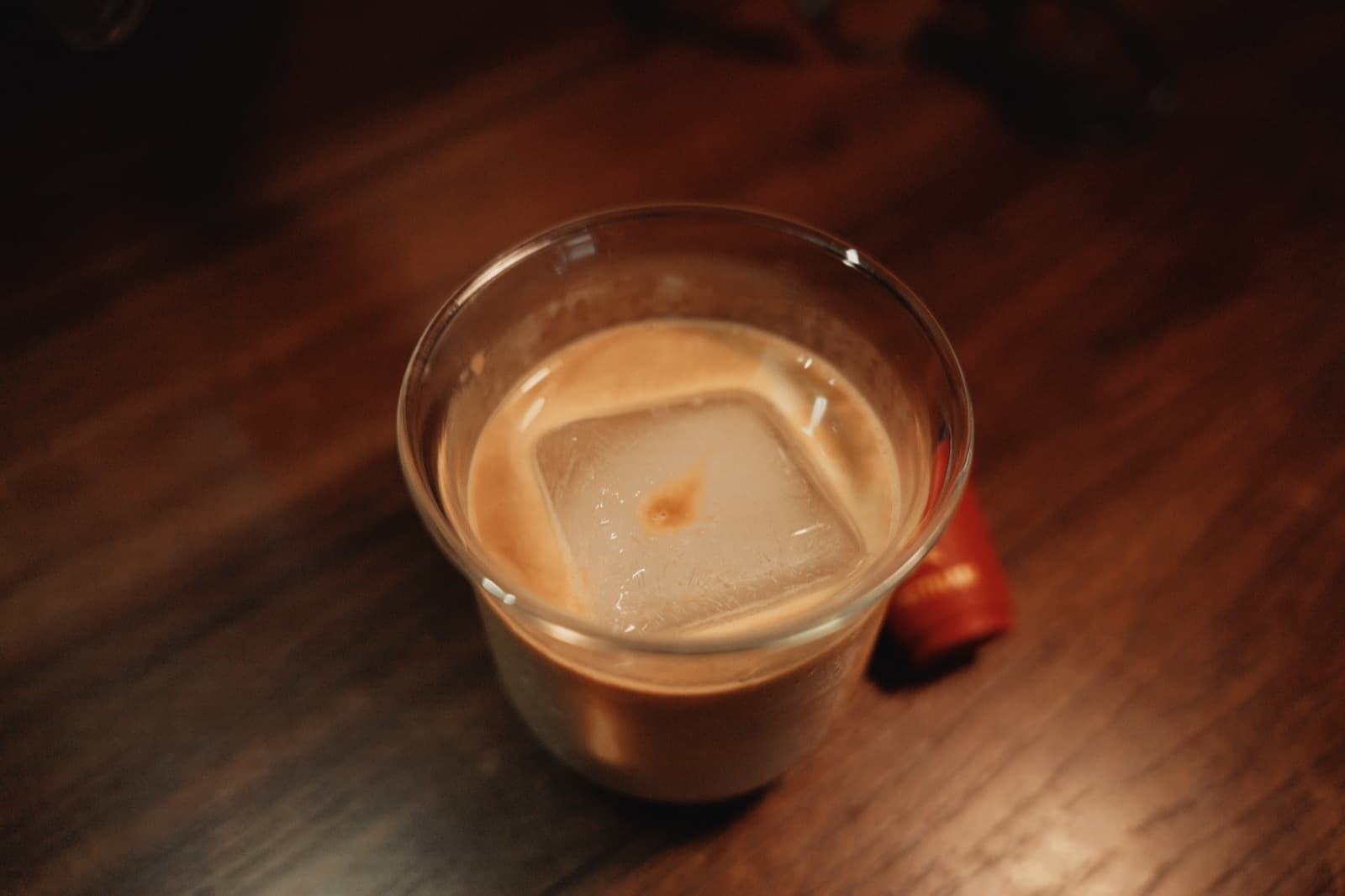 Iced coffee glass with a square ice cube, warm tones